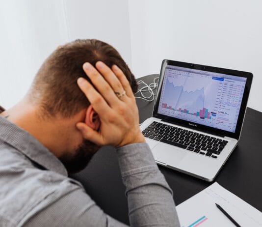 Dlaczego Twoje reklamy w Google Ads nie działają i jak to skutecznie naprawić Zestresowany mężczyzna przy biurku patrzy na spadki wykresów na laptopie