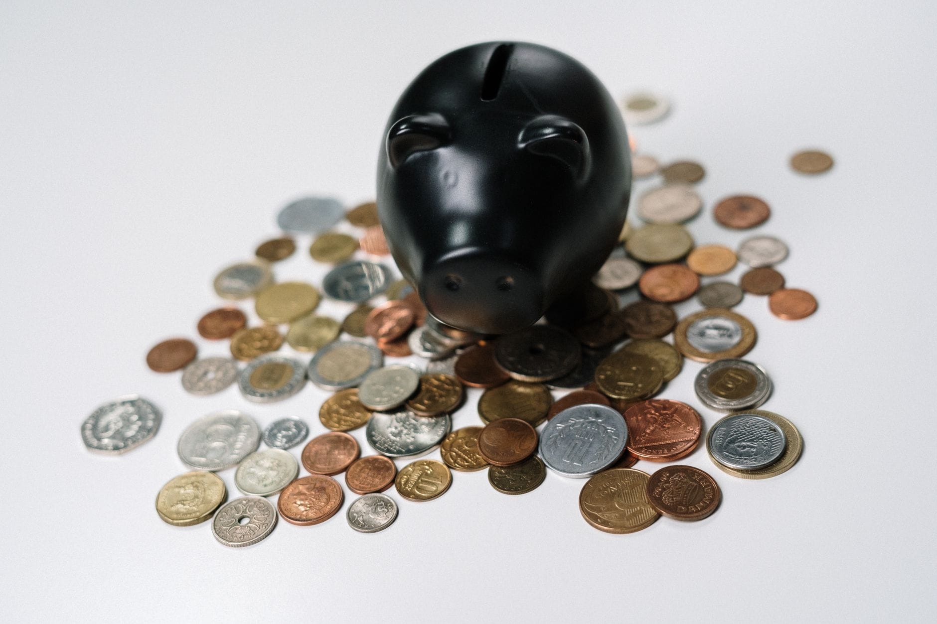 Czarna skarbonka otoczona monetami jako symbol oszczędności i finansów