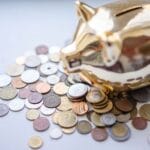 Złota skarbonka świnka otoczona monetami jako symbol poduszki finansowej