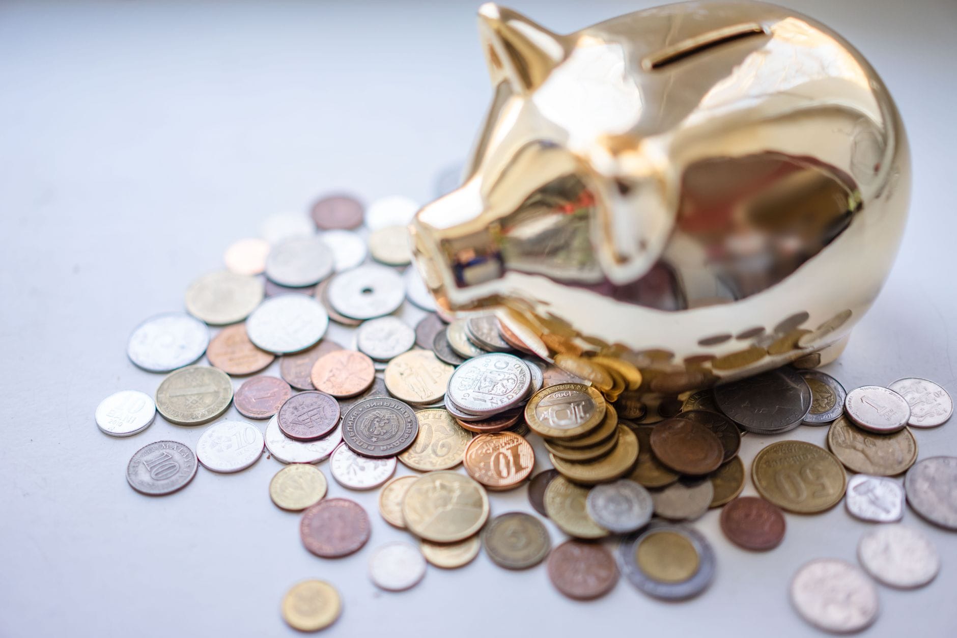 Złota skarbonka świnka otoczona monetami jako symbol poduszki finansowej
