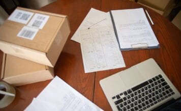 Jak założyć jednoosobową działalność gospodarczą krok po kroku w praktyce Stanowisko pracy z laptopem, dokumentami i paczkami do e-commerce